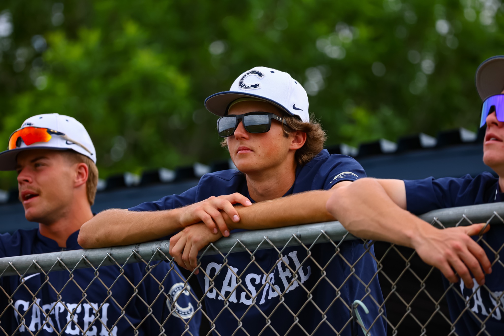 Casteel players watching from behind the dugout fence